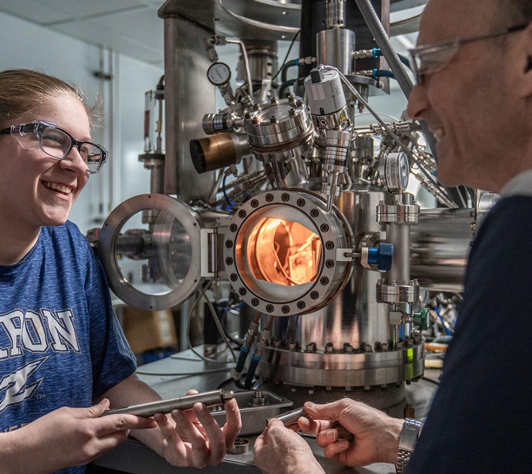 A student and professor working beside a vacuum chamber